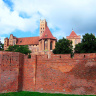 Оборонительные стены замка Тевтонского, за ними - часовня Девы Марии, в оконном проеме огромная статуя.