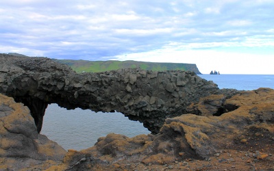 Каменная арка рядом с черным пляжем Вик